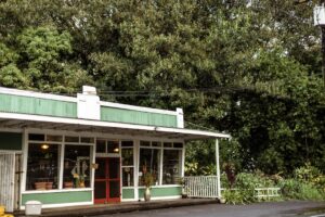 a small green and white building sitting next to a street