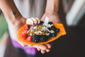 person holding blue berry with strawberry dessert shallow focus photography / Photo by Epicurrence o