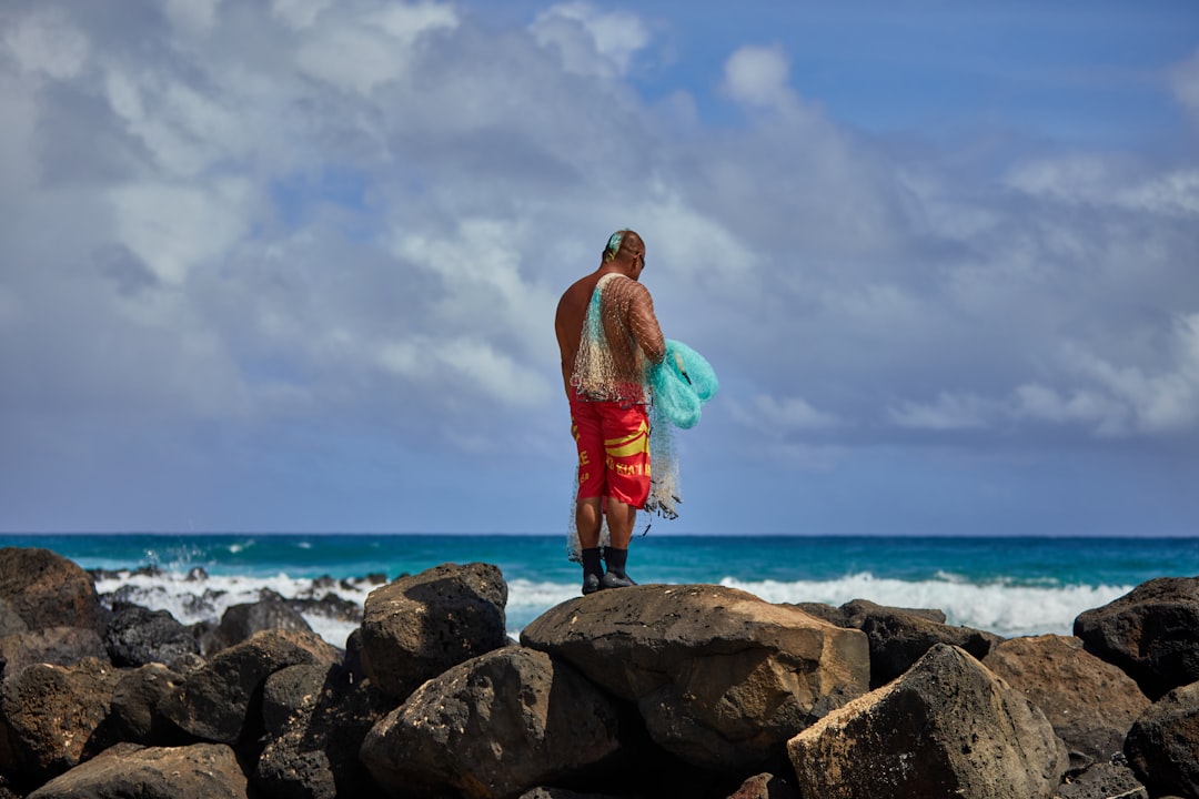 Man stands on rocks, holding a fishing net.