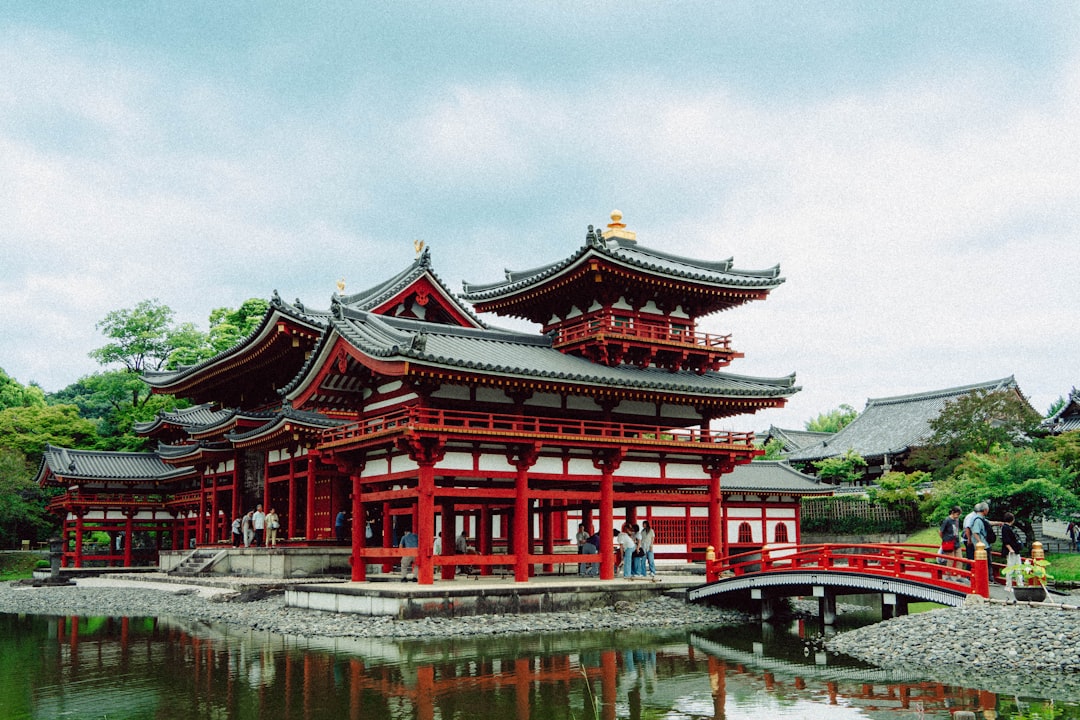 Historic japanese temple with red pillars reflected in water.