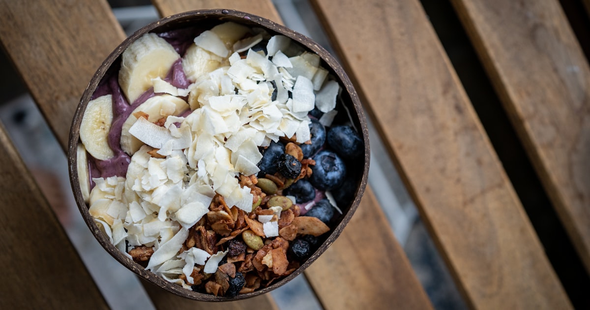 a bowl filled with granola, blueberries, and nuts