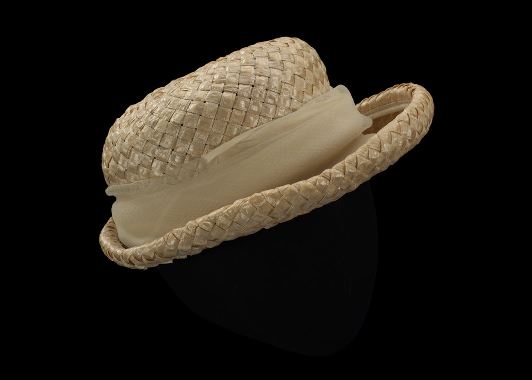 Woven straw hat with light fabric band on black background