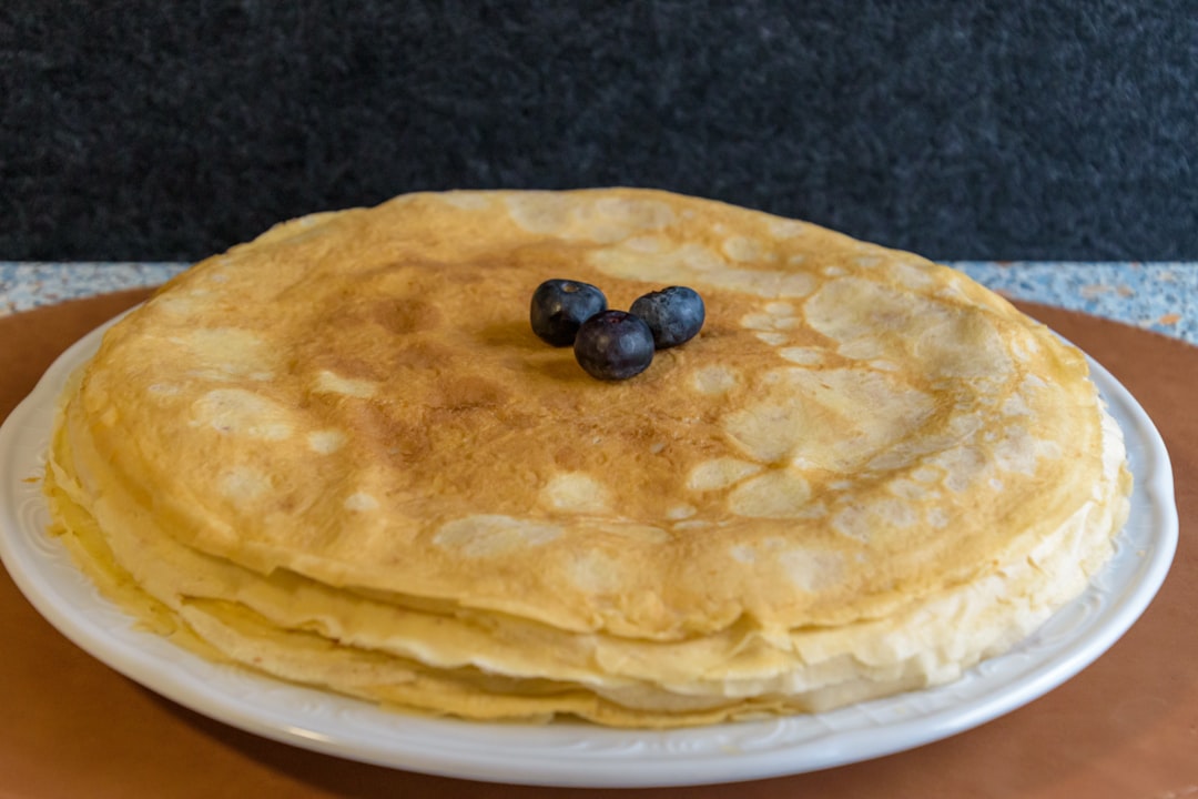 Stack of crepes topped with blueberries on a white plate