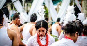 赤いレイを掛けた出演者が屋外の祭りで出番を待つ様子