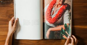 レイをかけた人物が載ったハワイの書籍を開いている様子